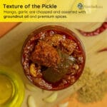 Spicy Andhra avakaya showing raw mango pieces in fiery oil